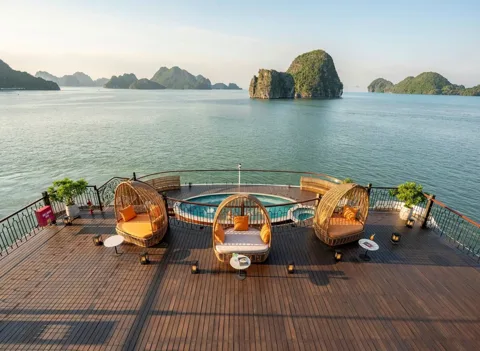 A luxurious cruise ship sailing through the iconic limestone karsts of Halong Bay at sunset