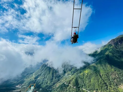 Sapa Glass Bridge extending over a mountain pass with clouds and distant peaks
