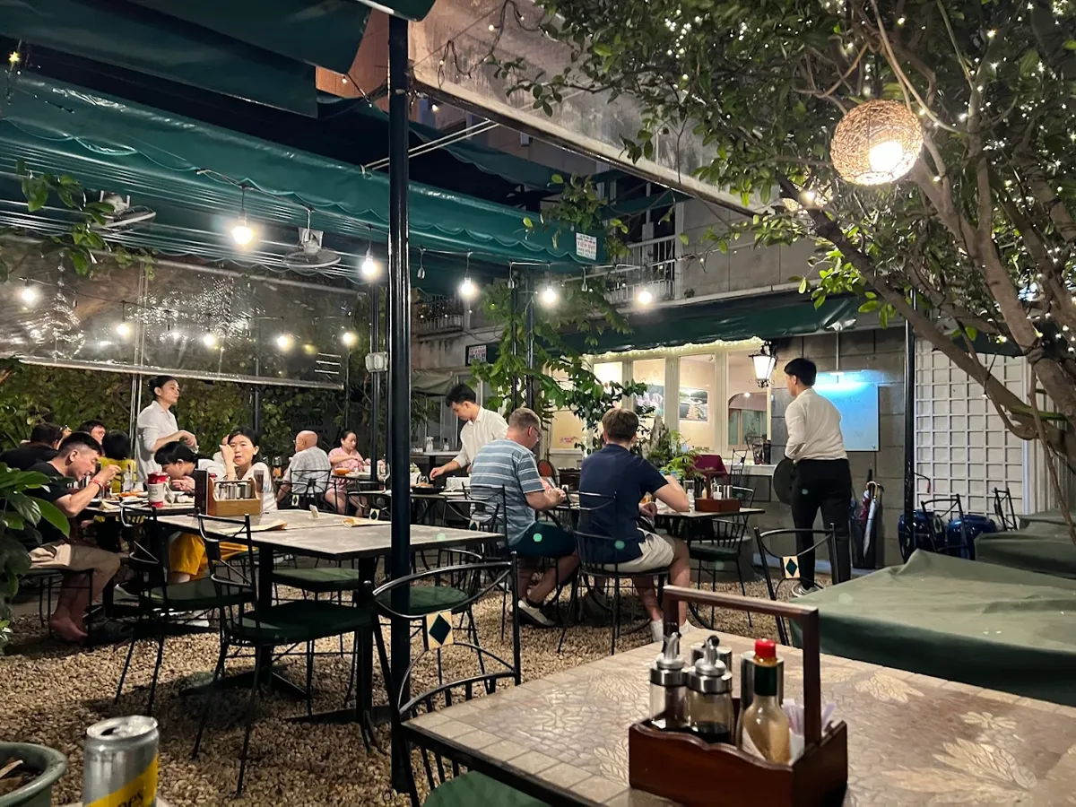 Outdoor bistro tables under greenery at Le Jardin