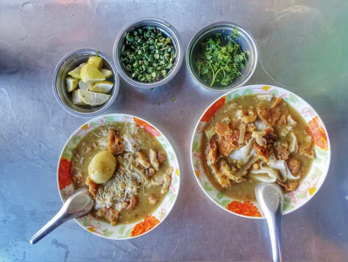 Assorted Burmese dishes including mohinga, lephet thoke and curry on a table