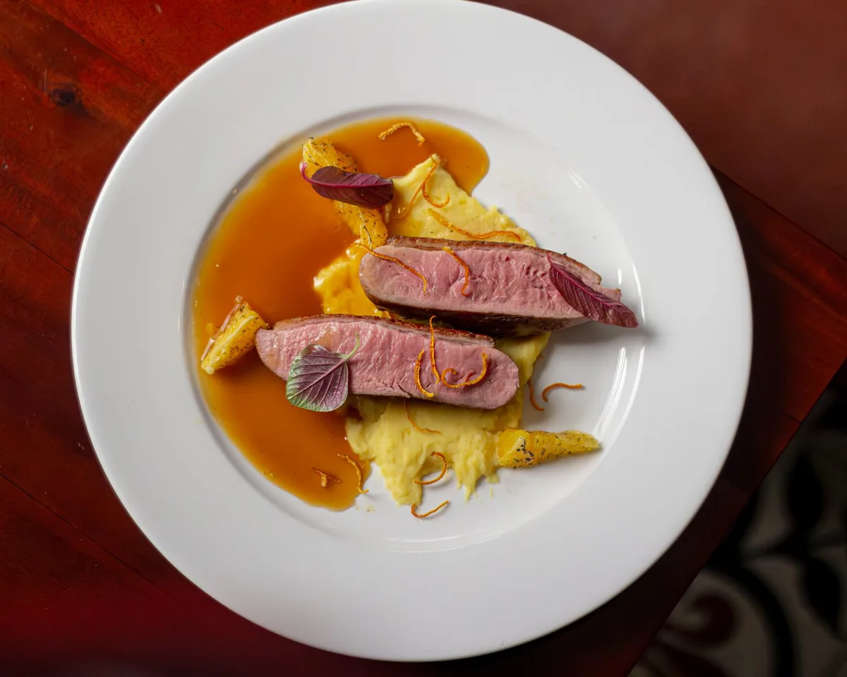 Crispy duck confit plated with garnish and sauce