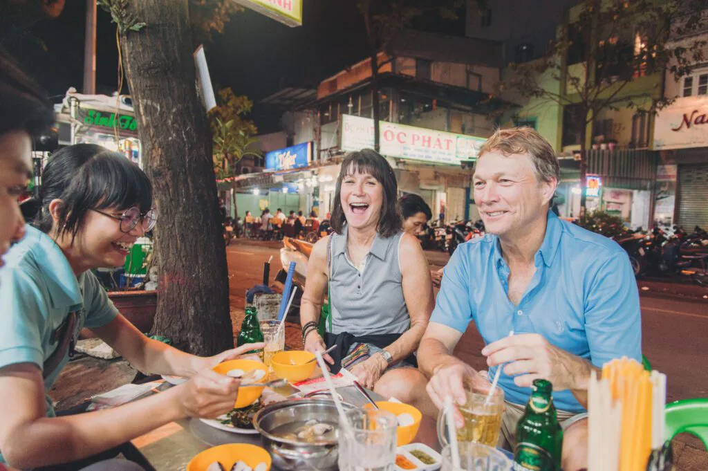 Busy night street food scene in District 1 Ho Chi Minh City with neon signs and food stalls