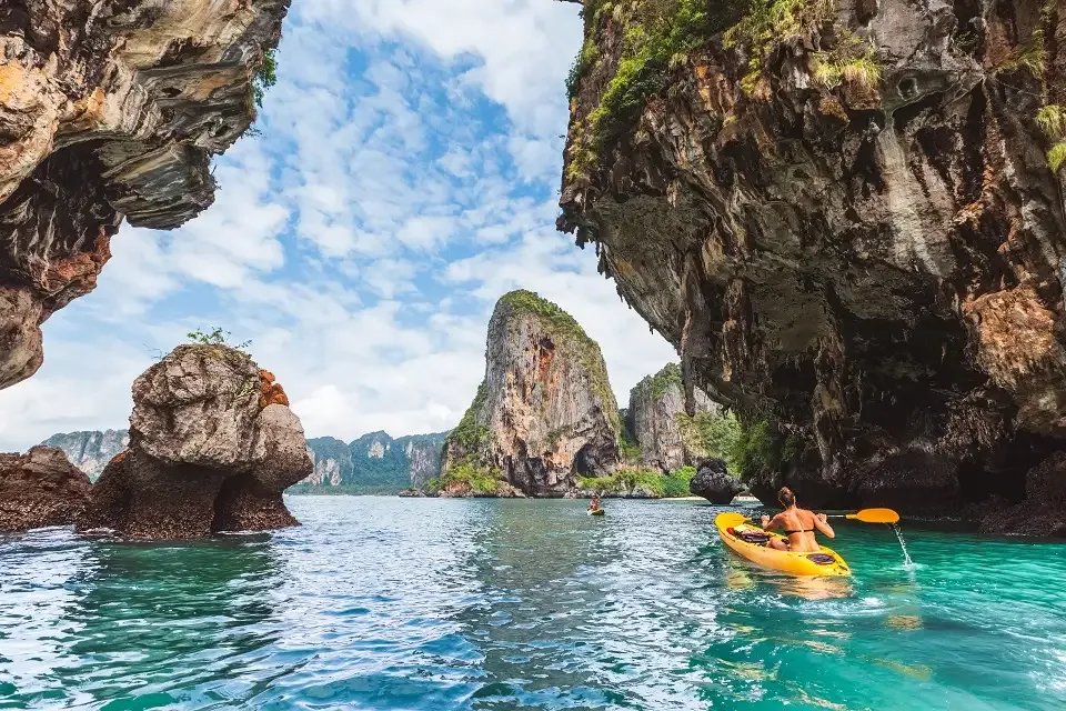 Longtail boats moored on a pristine white sand beach with towering limestone karsts and clear turquoise waters in Krabi, Thai