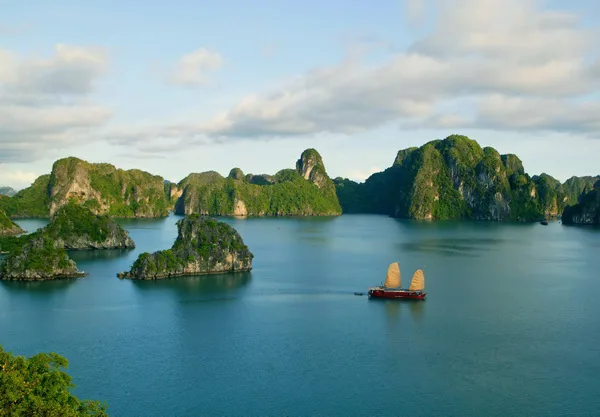 Limestone karsts and emerald waters of Halong Bay with a traditional boat